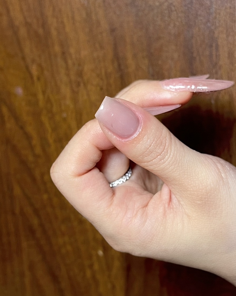 Une main présentant un ongle nude préparé et prêt pour la phase suivante du nail art détaillé.