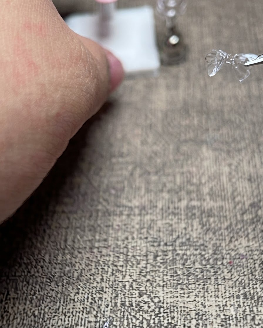 Une pince tenant un nœud 3D transparent délicat juste au-dessus dun présentoir dongles artificiels préparé.