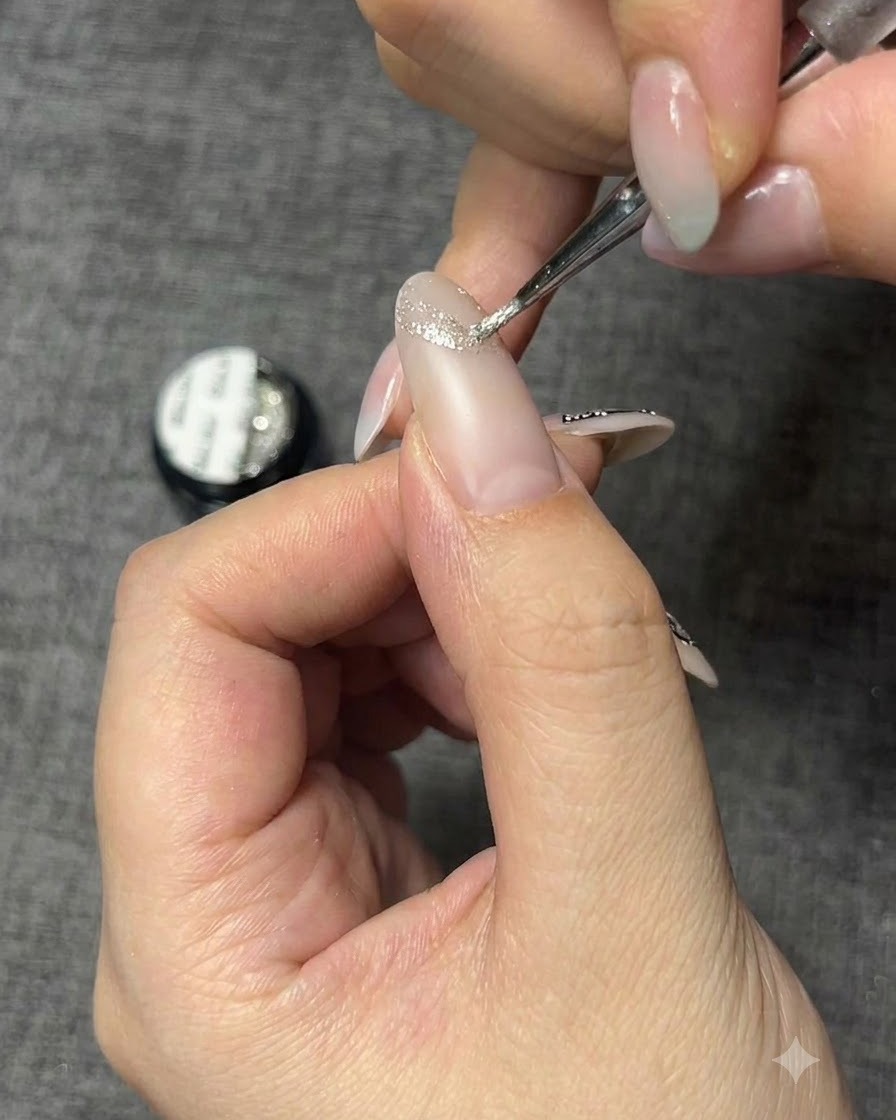Un pinceau de détail fin appliquant un gel argenté scintillant pour créer le contour dun papillon sur un ongle.