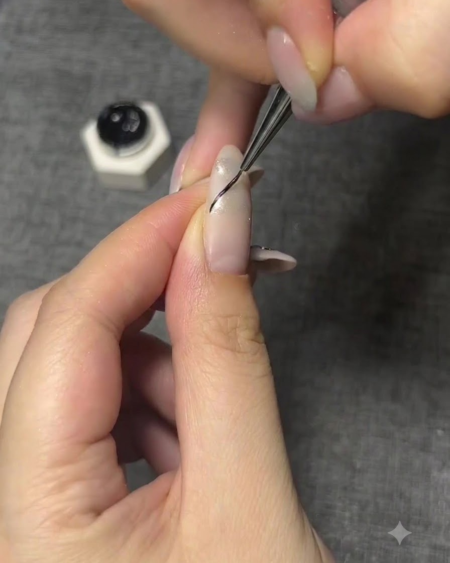 Un pinceau fin dessinant un fin contour noir incurvé pour une aile de papillon sur un ongle manucuré.