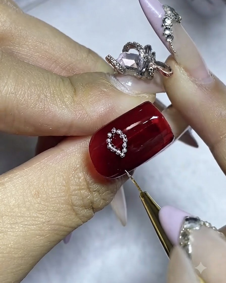 Un ongle avec un premier côté de nœud en perles argentées terminé et de la colle appliquée pour le second côté.