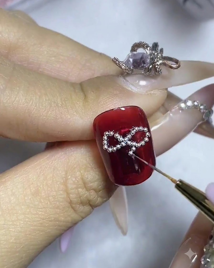 Gros plan sur un ongle montrant un strass central en cours dajustement au milieu de la structure en perles.