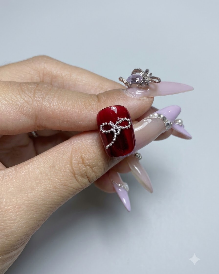 Un design de nœud en perles dacier terminé sur un ongle en gel rouge brillant vu de près.