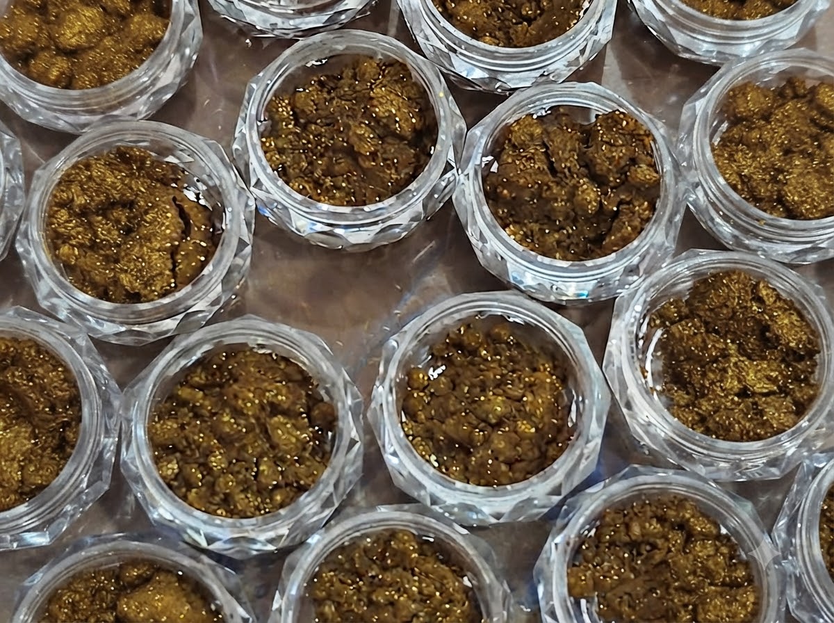 Un gros plan de plusieurs petits pots complètement remplis de poudre effet miroir bronze texturée.