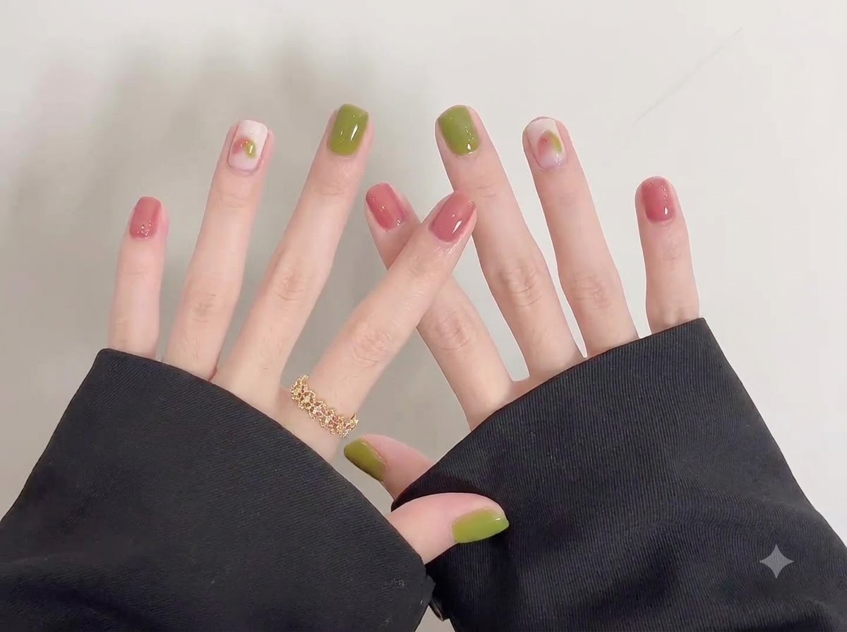 Un plan rapproché détaillé se concentrant sur les ongles verts et roses brillants de la main droite avec un délicat nail art doodle.