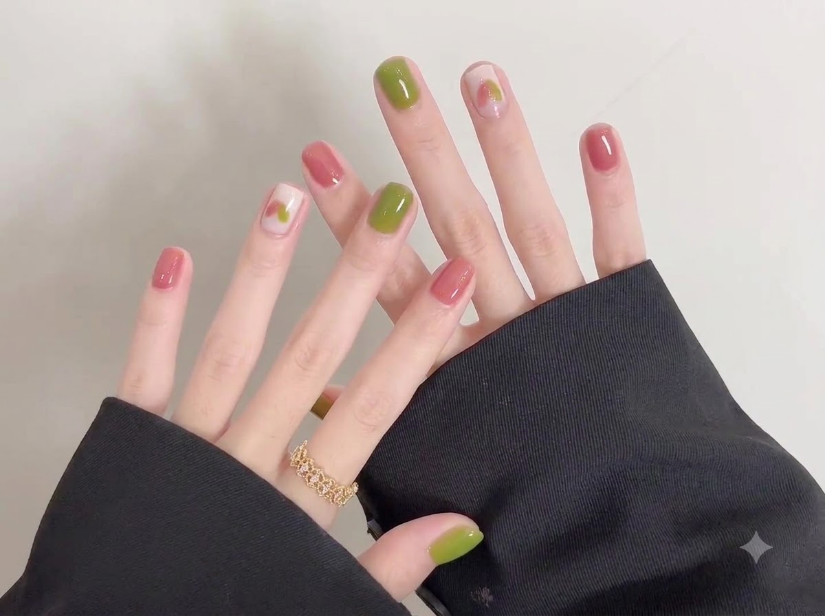 Une vue détaillée des doigts de la main gauche ornés dune bague dorée aux côtés des ongles en gel fraîchement vernis.