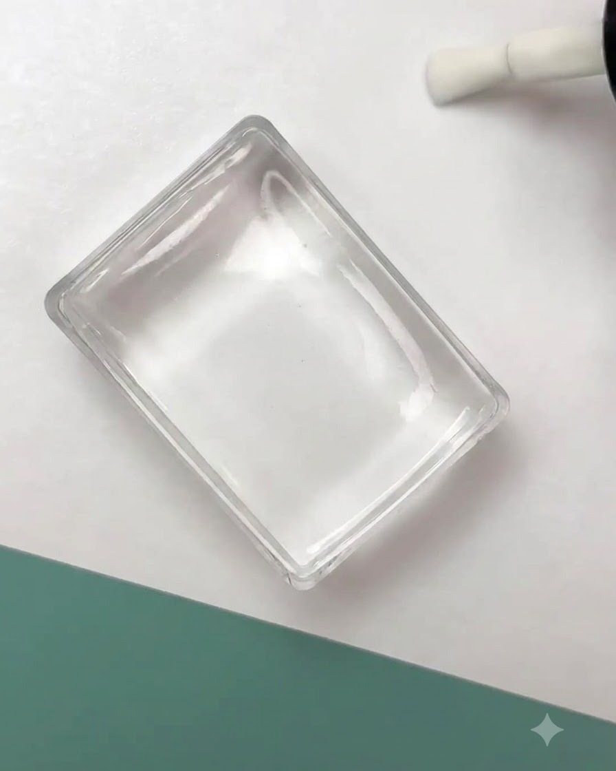 Un tampon en silicone transparent pressant un motif de contour floral noir sur une surface dongle préparée.