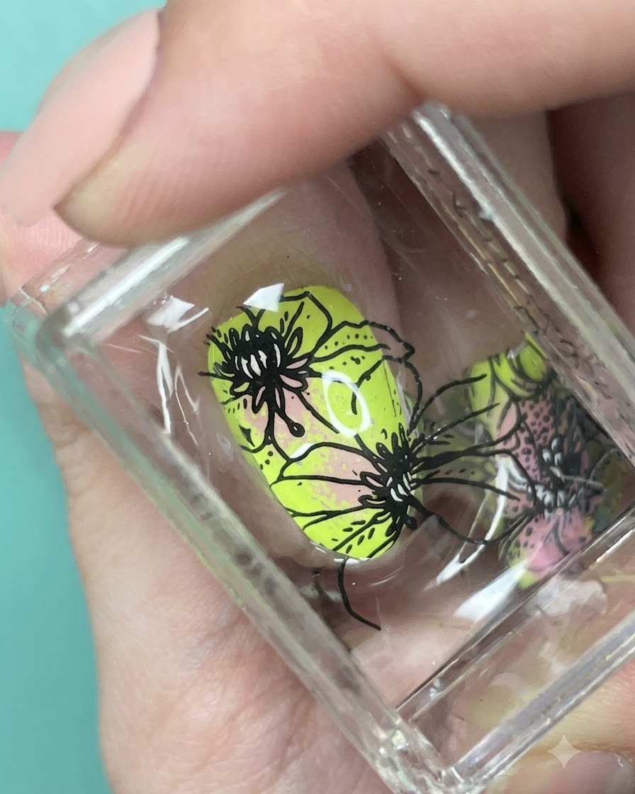 Vue rapprochée des motifs floraux noirs alignés sur longle en dégradé vert néon et rose sur un tampon.