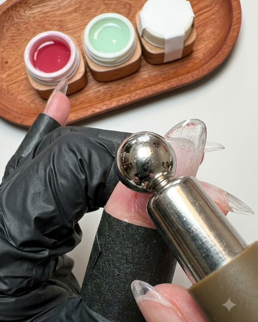 Un bâtonnet aimanté planant de près au-dessus de la surface dun ongle en gel pailleté humide.
