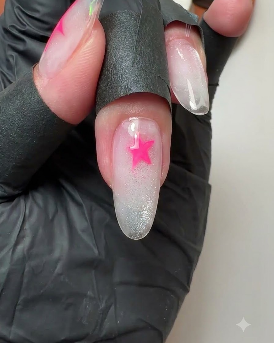 Gros plan dun ongle du majeur montrant une étoile rose vibrante fraîchement peinte.