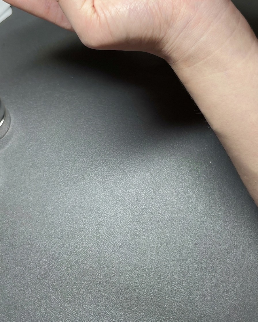 Une main tenant un petit aimant en néodyme près dun ongle enduit de gel cat-eye vert métallique, créant une ligne réfléchissante brillante.