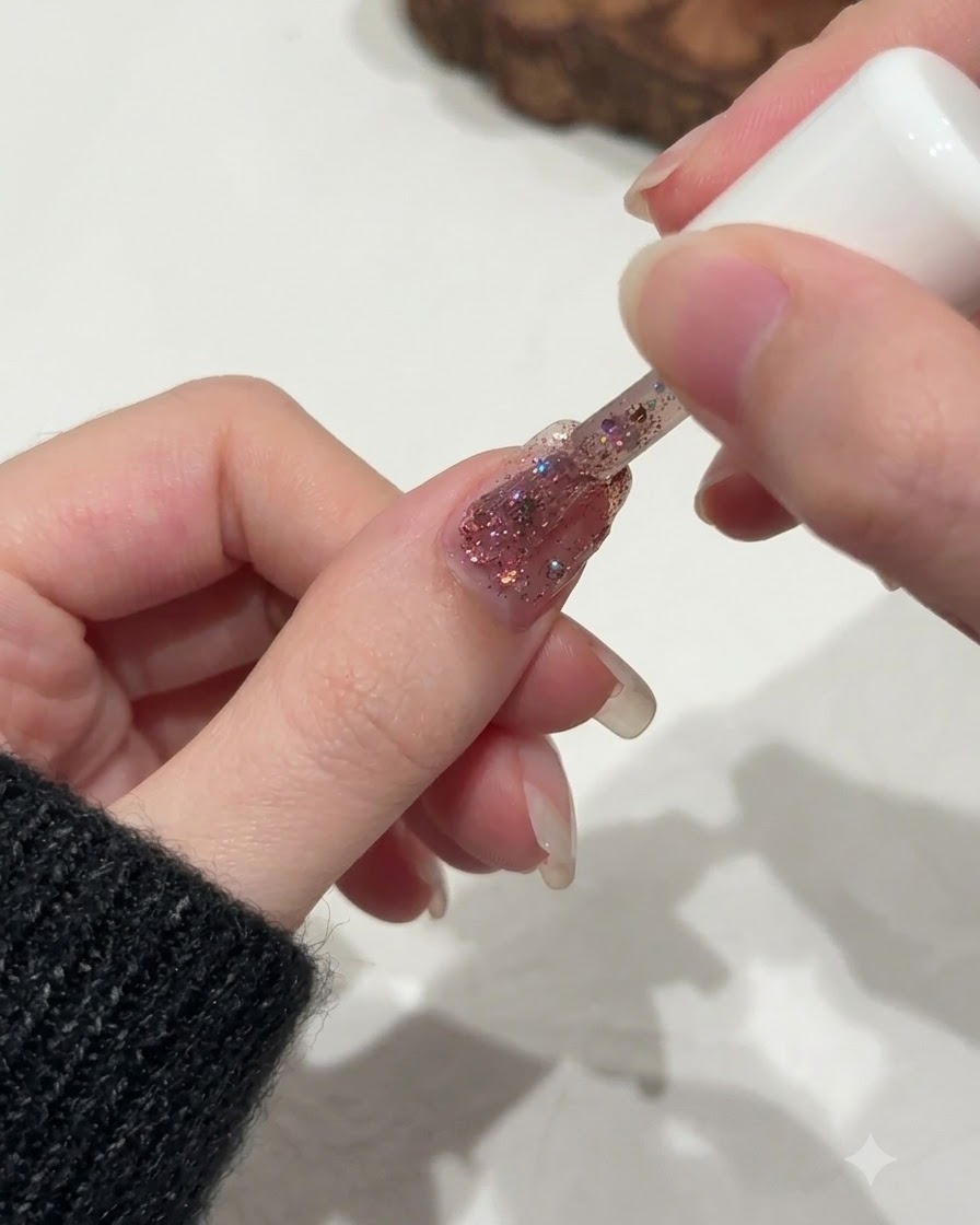 Un pinceau affinant délicatement la distribution des paillettes près de la ligne des cuticules dun ongle.