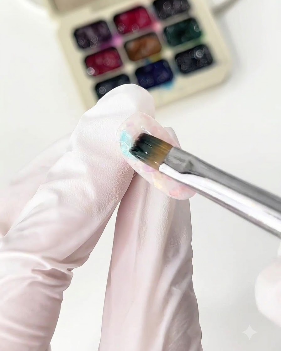 Un pinceau fin appliquant du gel verre bleu sur le bout dun ongle.