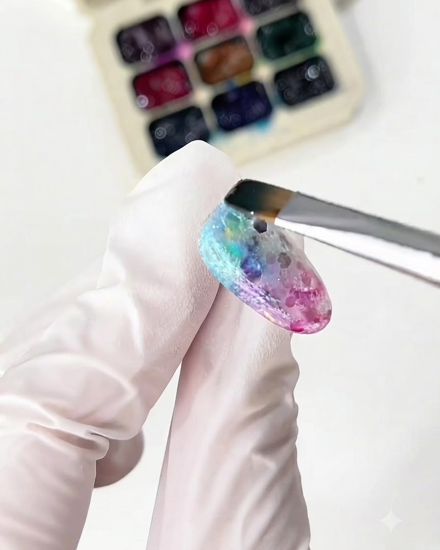 Un pinceau fin appliquant des gels verre jaune et vert sur longle.