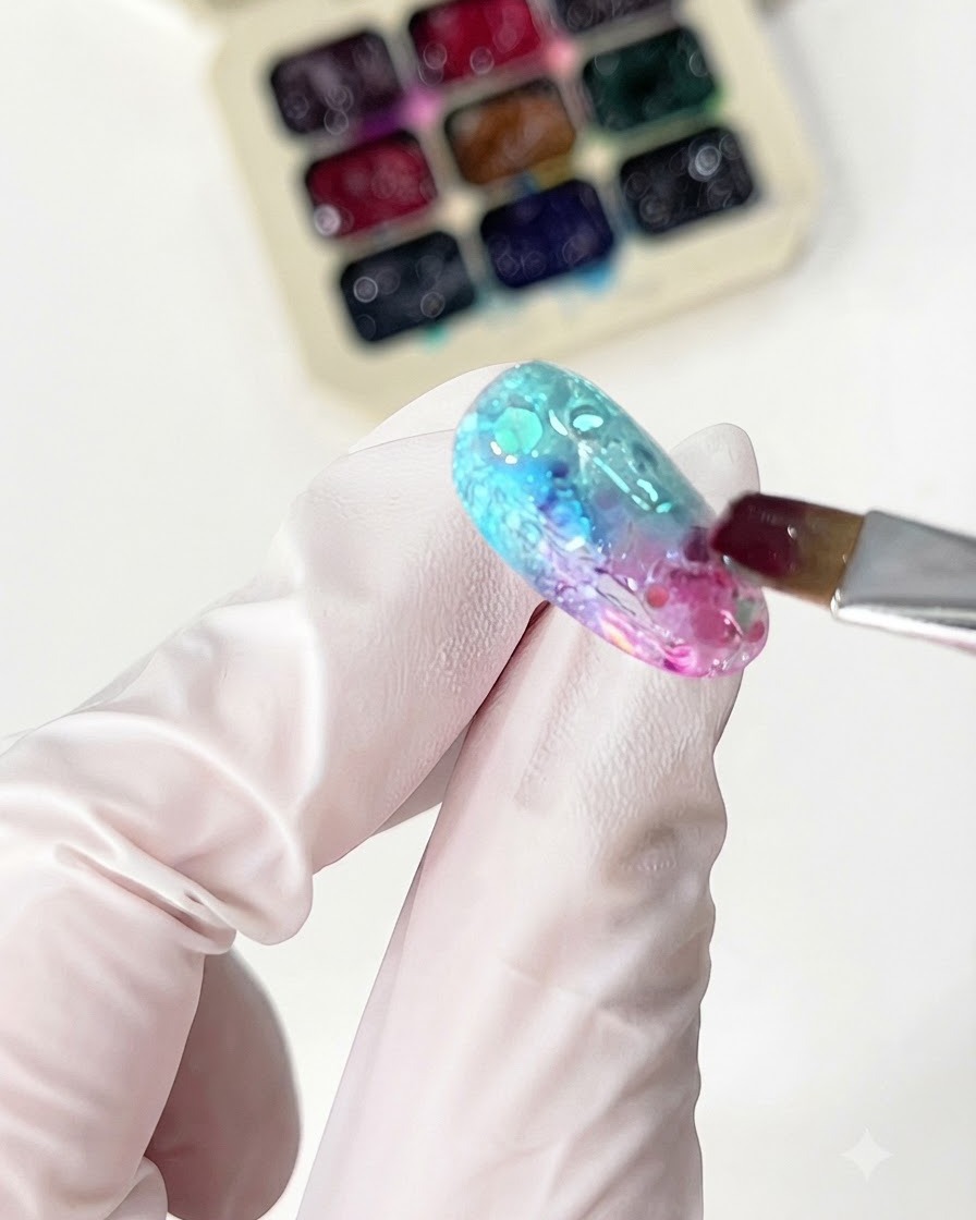 Un pinceau fin appliquant du gel verre orange pour compléter le design en dégradé.