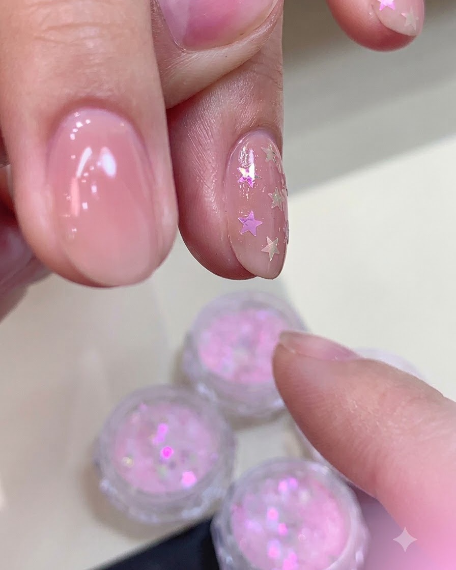 Application dune couche épaisse de top coat mat sur un ongle décoré de paillettes détoiles incurvées.