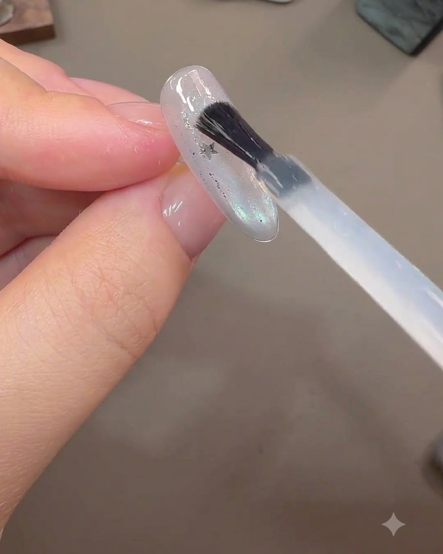 Un pinceau appliquant une couche épaisse de gel de construction sur des paillettes détoiles incrustées sur une extension dongle finie.