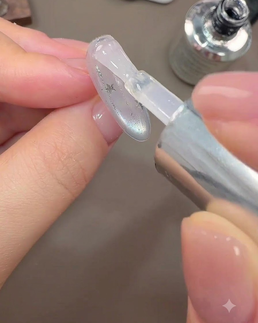 Un pinceau appliquant une couche finale de top coat brillant sur un design dongle galaxie.