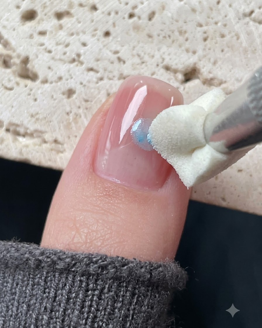 Un outil destampage en silicone appliquant du gel verre bleu autour dun autocollant étoile sur un ongle.