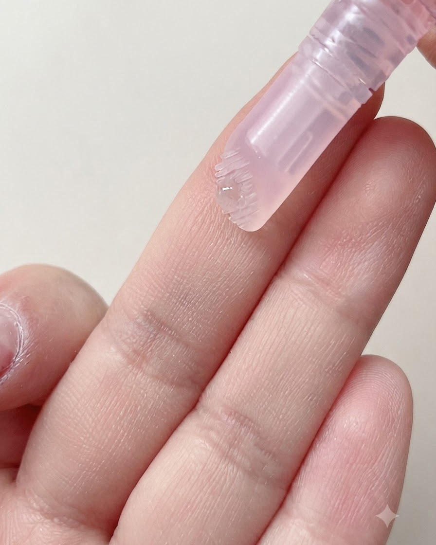 La tête de brosse souple dun stylo pour cuticules versant une goutte de sérum hydratant sur un doigt.