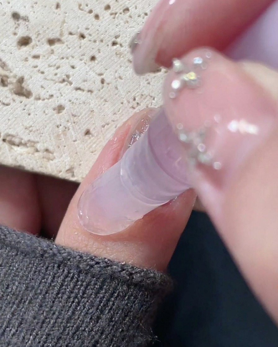 Un stylo huile pour cuticules appliqué autour du bord dun ongle fini pour hydrater la peau.