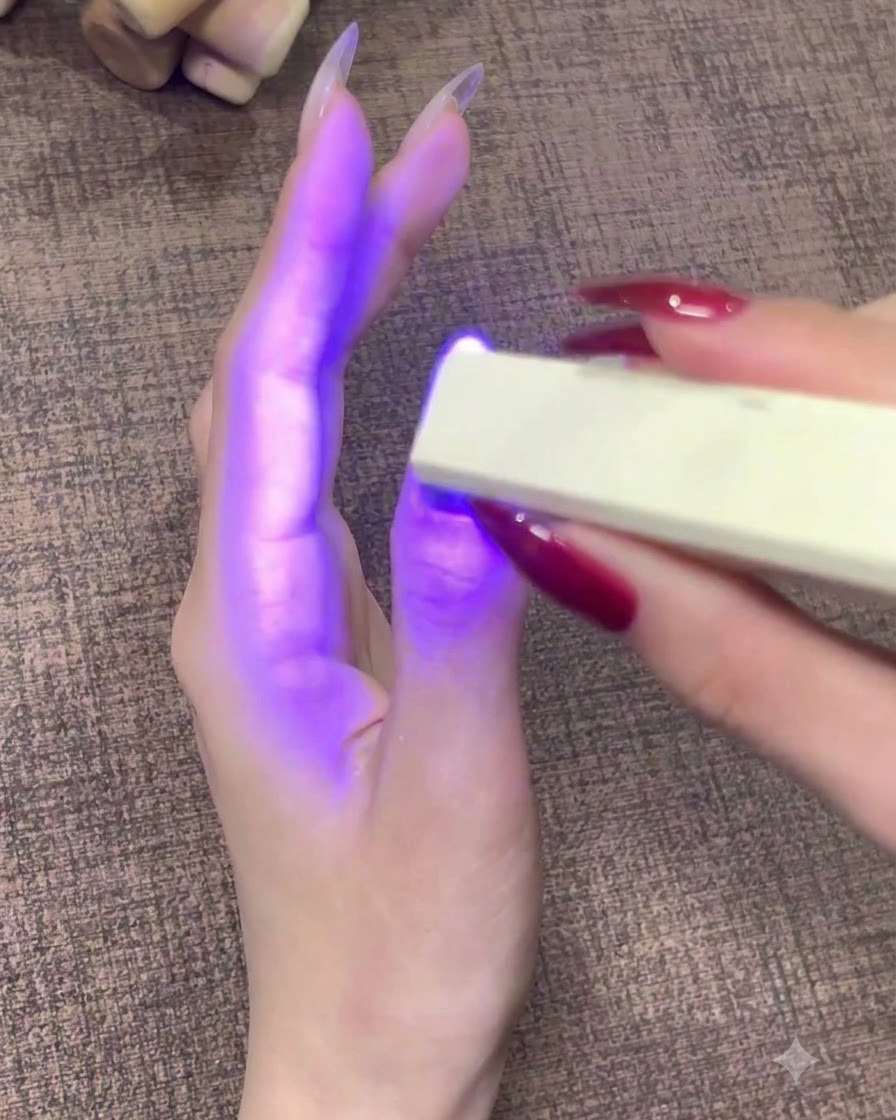 Une lampe à ongles UV LED portable diffusant une lumière violette sur un ongle de pouce fini.
