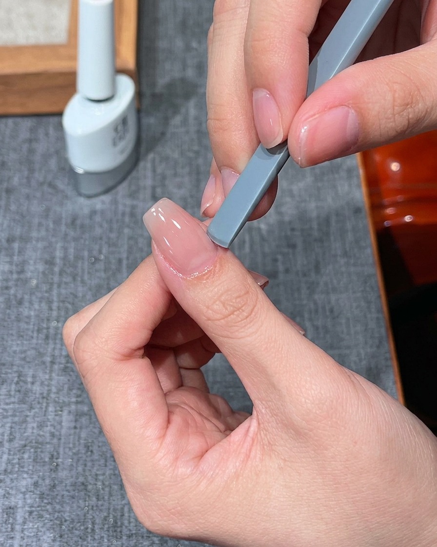 Un doigt placé sous une petite mini lampe UV/LED pour la catalysation.