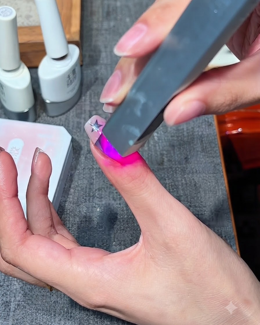 Une mini lampe UV/LED portable pour ongles catalysant un design en gel sur un doigt.