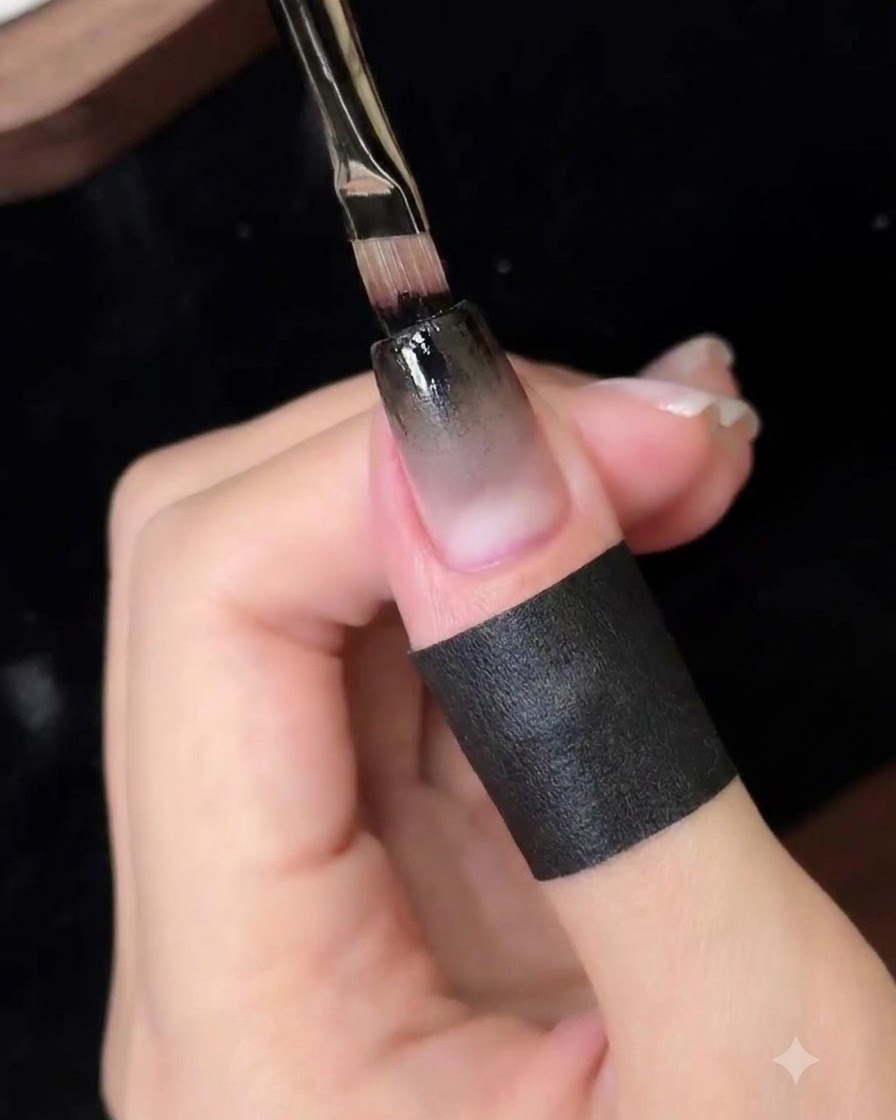 Un pinceau de détail fin appliquant une couche concentrée de gel noir sur le bord supérieur de longle.