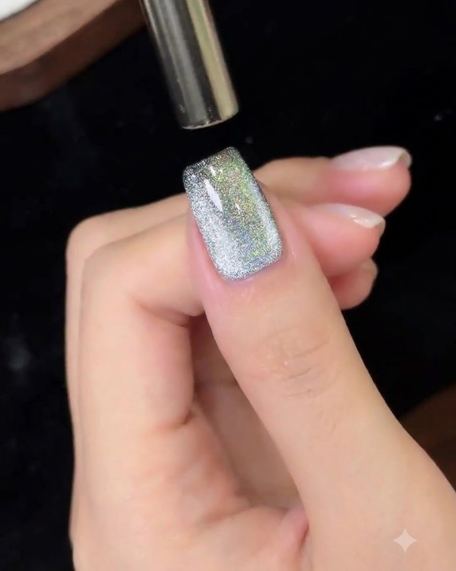 Un outil magnétique déplacé de haut en bas sur un ongle en gel cat eye.