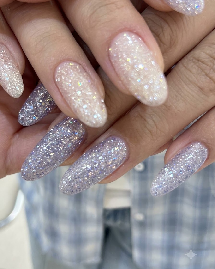 Gros plan sur des mains aux doigts entrelacés affichant des ongles en gel pailleté rose nude et violet brillant.