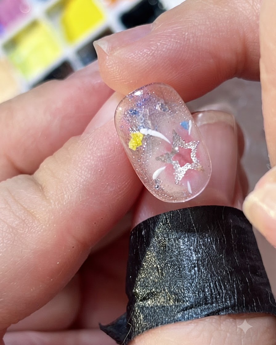 Gros plan de lignes blanches et jaunes peintes à la main rayonnant comme des feux dartifice sur un ongle décoré.