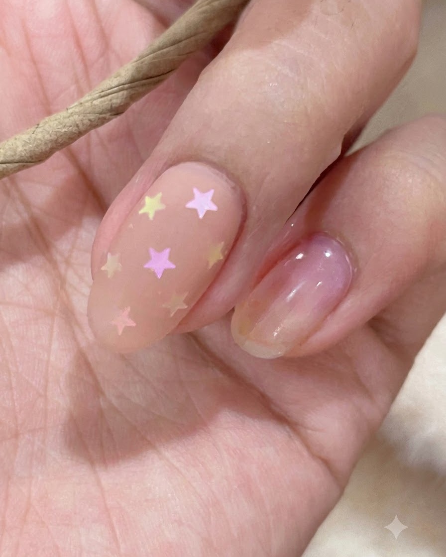 Gros plan dun bâtonnet de nuancier présentant des teintes de vernis gel nude et rose.