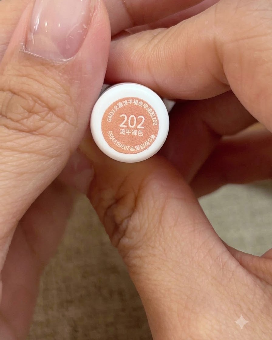 Vue rapprochée de mains tenant le flacon de vernis gel rose pêche miellé numéro 202.