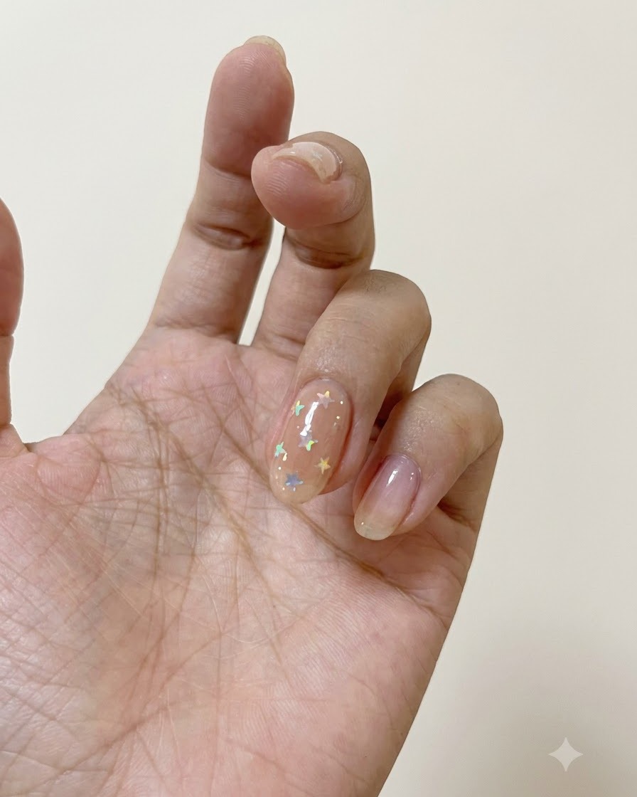Un pinceau à ongles appliquant un top coat mat sur un ongle décoré détoiles polarisées.
