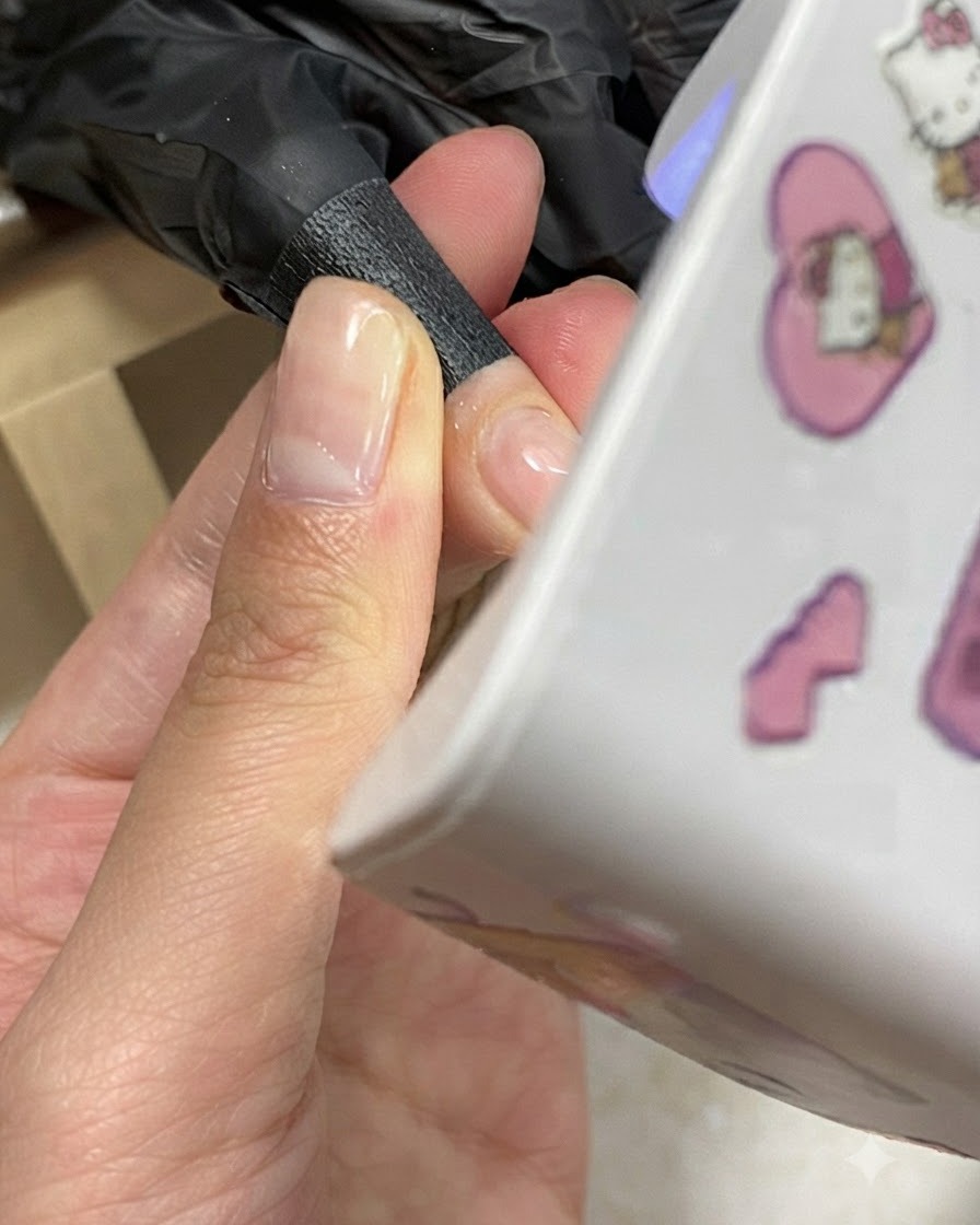 Une main positionnée sous une mini lampe UV/LED compacte pendant le processus de catalyse du gel.
