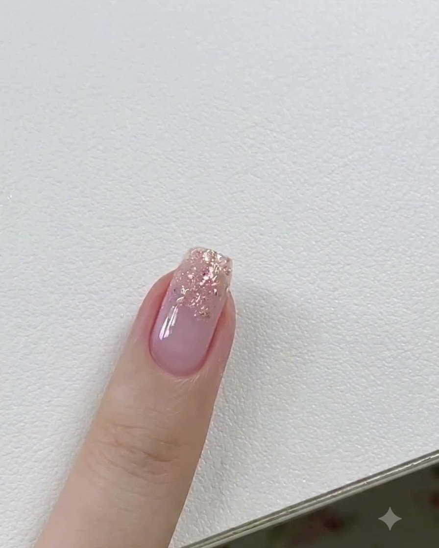 Un pinceau à gel appliquant une fine couche de gel de construction transparent sur un ongle aux accents pailletés.