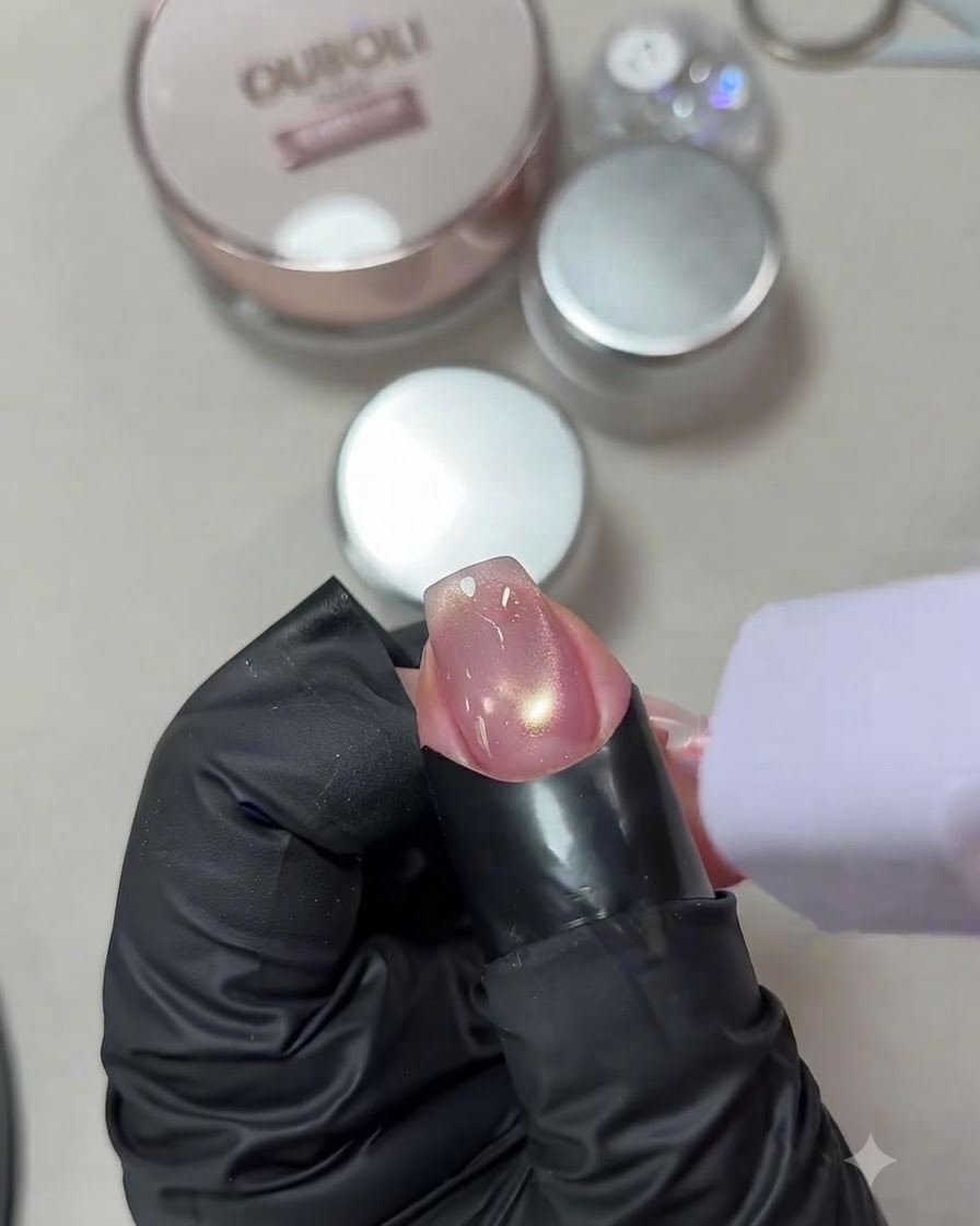 Un ongle avec un motif en gel œil de chat lumineux catalysé sous une petite lampe UV/LED violette portable.
