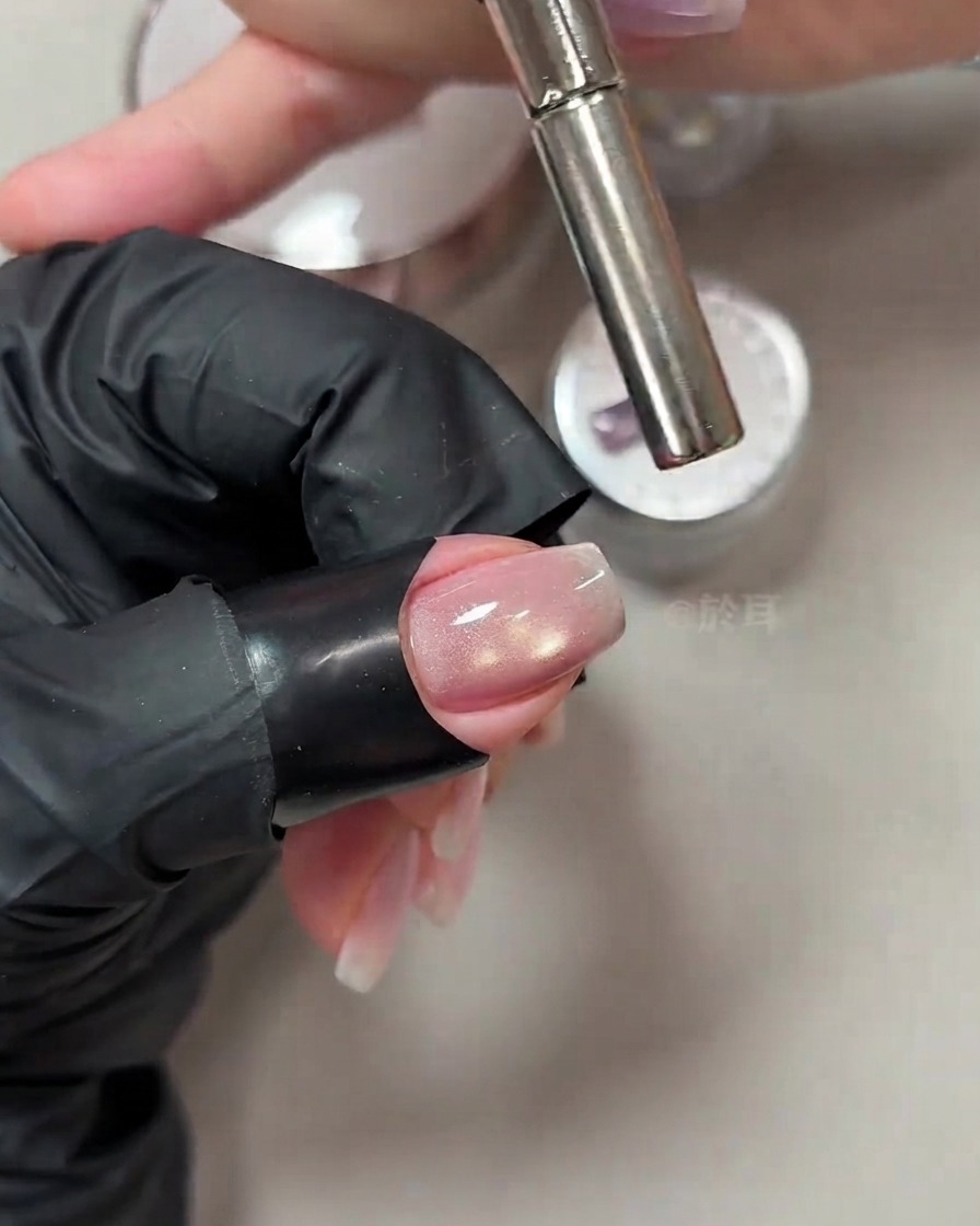 Un aimant cylindrique tenu près du bout dun ongle manucuré pour manipuler le scintillement œil de chat.