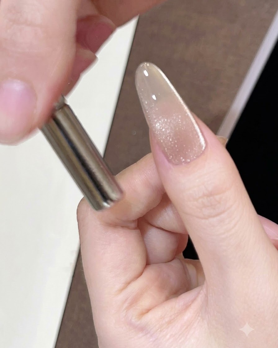 Un aimant cylindrique tenu près du côté dun ongle peint pour déplacer les reflets magnétiques.