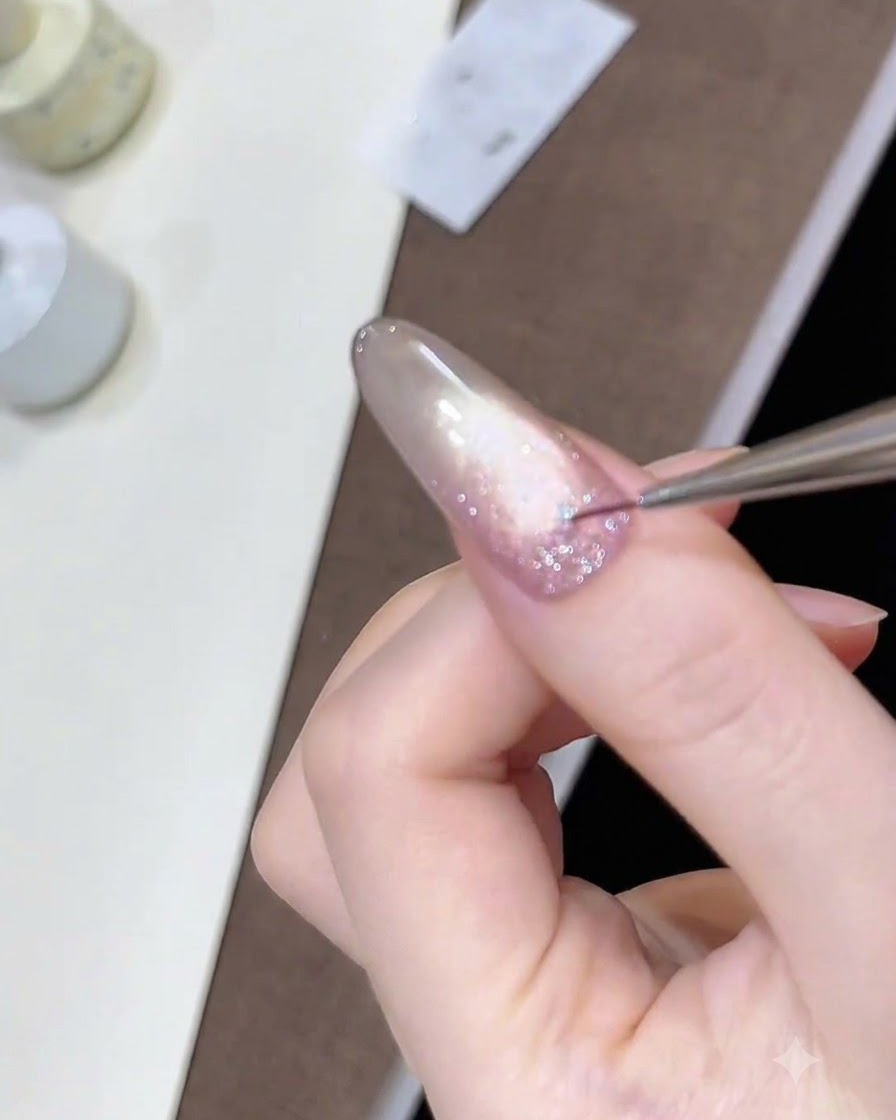 Un pinceau fin de détail plaçant de minuscules sequins détoiles sur la couche de gel pailleté humide.