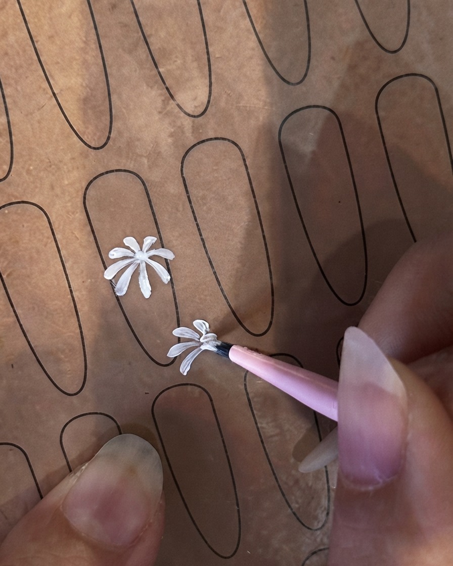Un pinceau fin commençant un deuxième pétale blanc plus petit sur une feuille dongle dentraînement.