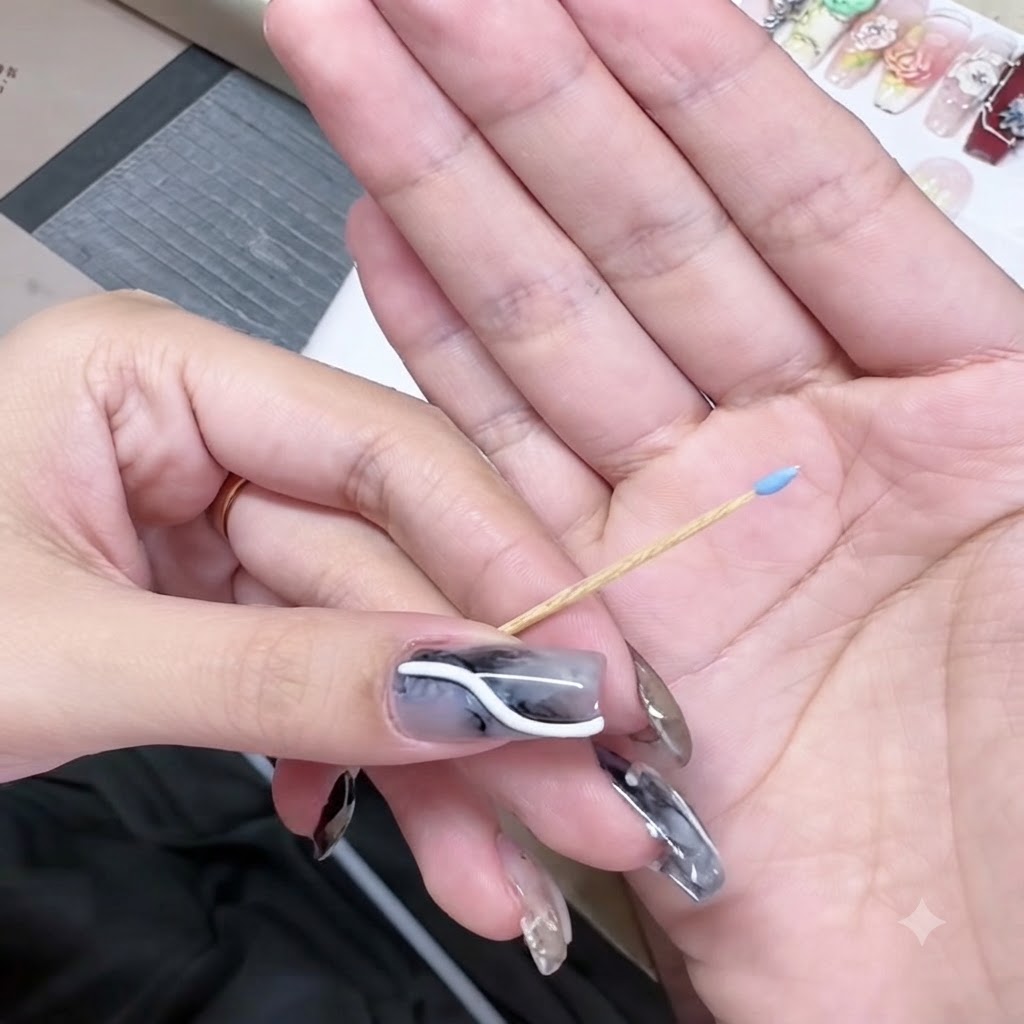 Un cure-dent tenu dans une main avec une minuscule perle de gel bleu sur sa pointe.