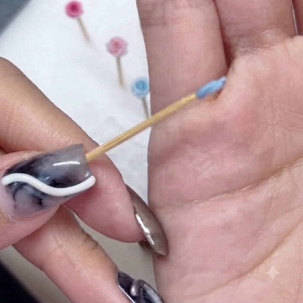 Gros plan dun minuscule pétale bleu sculpté enroulé autour de la pointe dun cure-dent en bois.
