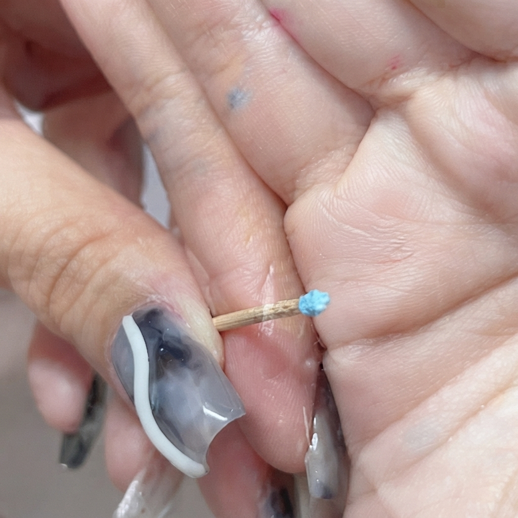 Un tout petit bouton de rose bleue fermé sculpté au bout dun cure-dent.