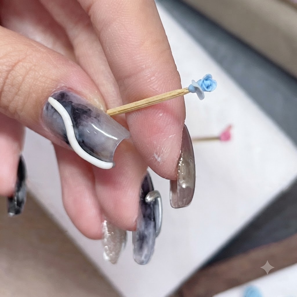 Un petit bouton de rose bleue sur un cure-dent tenu entre les doigts, montrant le placement dun nouveau pétale.