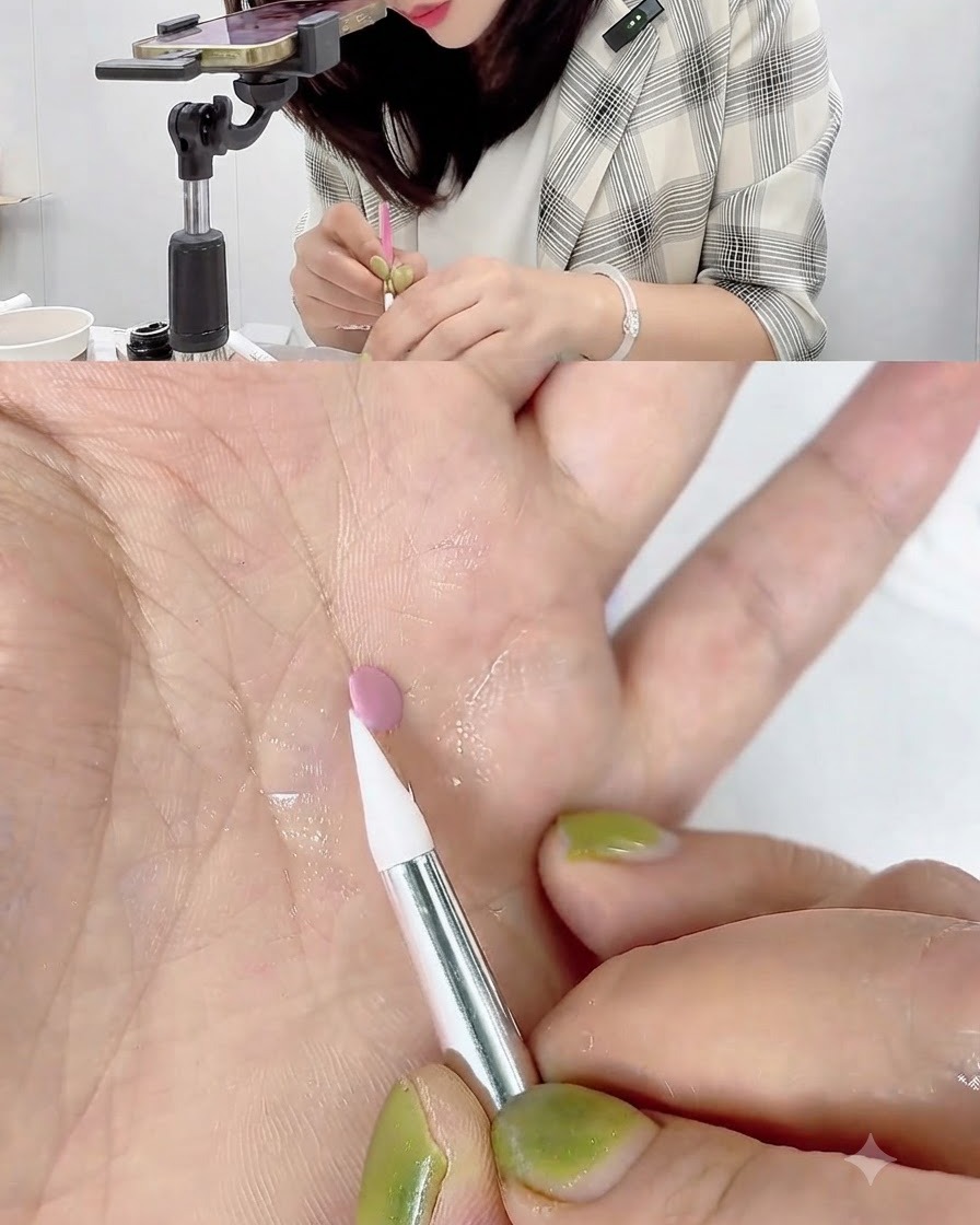 Un stylo de sculpture en silicone blanc touchant et roulant le bord dun petit disque de gel rose reposant sur une paume.