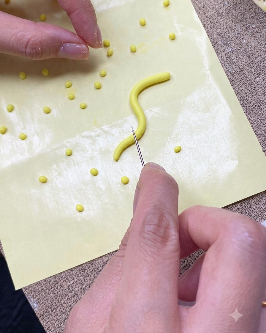 Gros plan de mains coupant une bande de gel jaune en petites portions sur un tapis en silicone avec une aiguille.