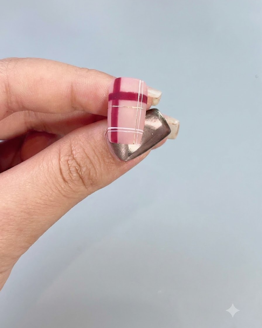 Gros plan dun ongle décoré présentant un motif à carreaux rouge et blanc avec des accents dorés.