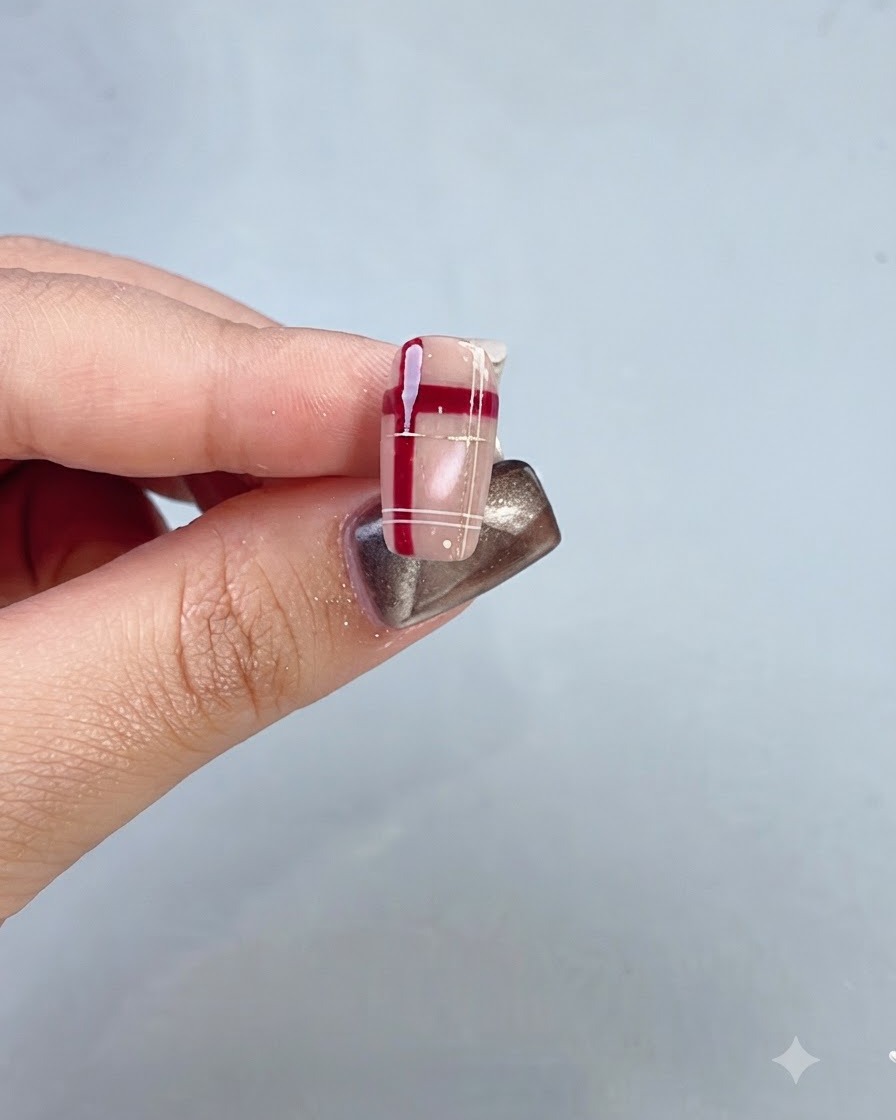 Gros plan dun ongle complété présentant un réseau de cristaux rouges et un design à carreaux.